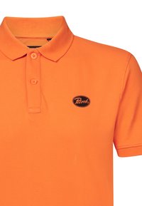 Oranžová polo košile vyrobená z strukturované tkaniny, s tříknoflíkovou légou a černým oválným logem na levé hrudi.