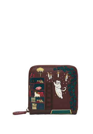 Portafoglio marrone con gatto bianco ricamato che raggiunge candele appese, scaffale pieno di libri e regali, e edera verde di lato.