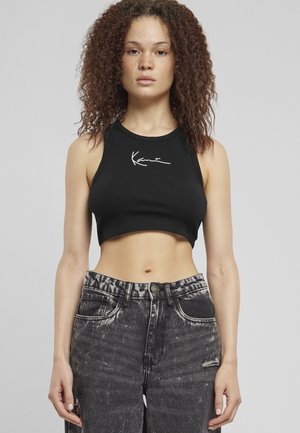 Crop top noir côtelé avec un col rond et un motif signature blanc. Associé à un jean en denim noir déchiré et taille haute.