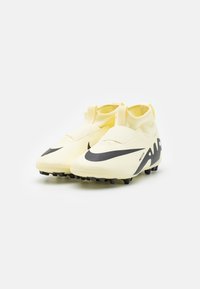 Botas de fútbol amarillas con un diseño elegante, que cuentan con un distintivo swoosh negro de Nike, parte superior texturizada y tacos negros en la suela para mayor tracción.