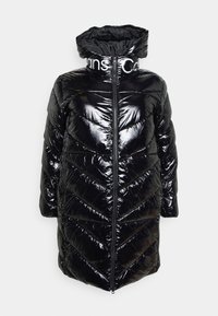 Schwarze Daunenjacke mit glänzender, gesteppten Oberfläche, hohem Kragen und einem Reißverschluss auf der Vorderseite. Verfügt über weiße Markenbezeichnung am Kragen.