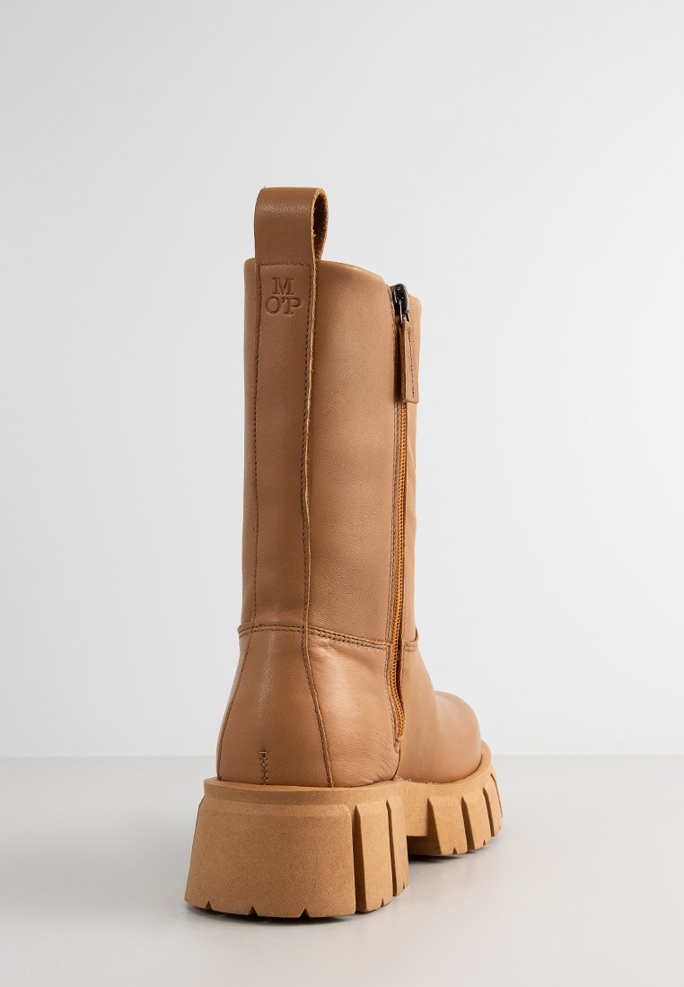 Braunleder-Ankle-Boot mit robuster Sohle, seitlichem Reißverschluss und Zugschlaufe, der über eine glatte Textur und minimale Details verfügt.