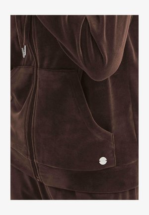 Pruun veluurne lukkuga jakk, millel on ees taskud, peen sära ja metallist aktsentnupp tasku lähedal. Pehme, tekstureeritud kangas.