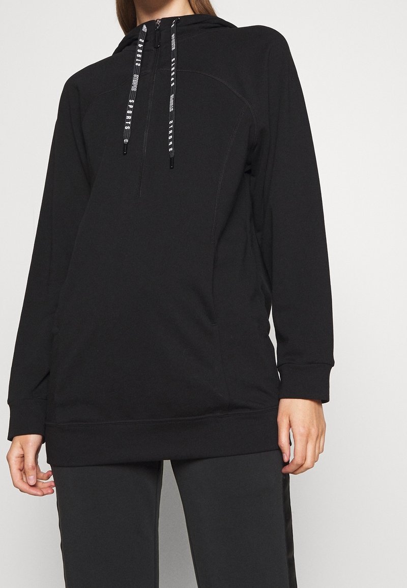 Sudadera negra con capucha y diseño de media cremallera, que presenta cordones de contraste, puños acanalados y un ajuste relajado. Textura de tela suave.