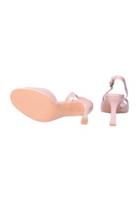 Scarpe con tacco alto in vernice rosa, design con apertura sulla punta, sottile cinturino alla caviglia e tacco curvo. Texture liscia con un leggero effetto lucido.