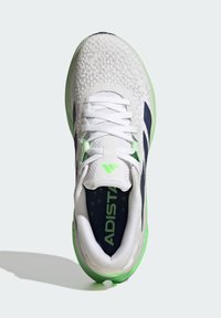 White athletic shoe with a textured mesh upper, green accents, dark blue logo, and lace closure. Features a cushioned heel and lightweight sole.