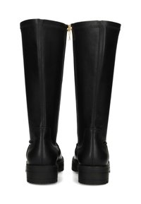 Par de botas altas de cuero negro con suelas gruesas y cremalleras traseras visibles sobre un fondo blanco.