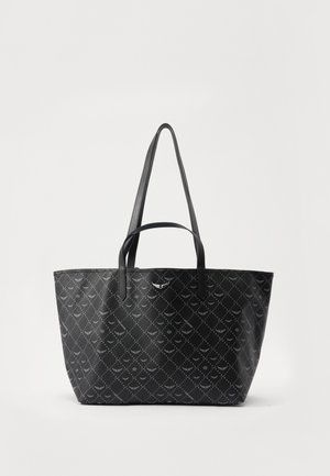 Sac cabas noir avec un motif géométrique répétitif et deux longues anses, posé sur un fond blanc uni.