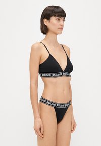 Čierny bikiny set so trojuholníkovým braletom s tenkými ramienkami a elastickým pásom s logom, v kombinácii s nohavičkami v štýle thong.
