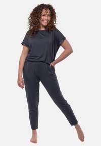 Donkergrijze loungewear set met een losse, korte mouw top en taps toelopende broek met zijzakken, gemaakt van zachte, rekbare stof.