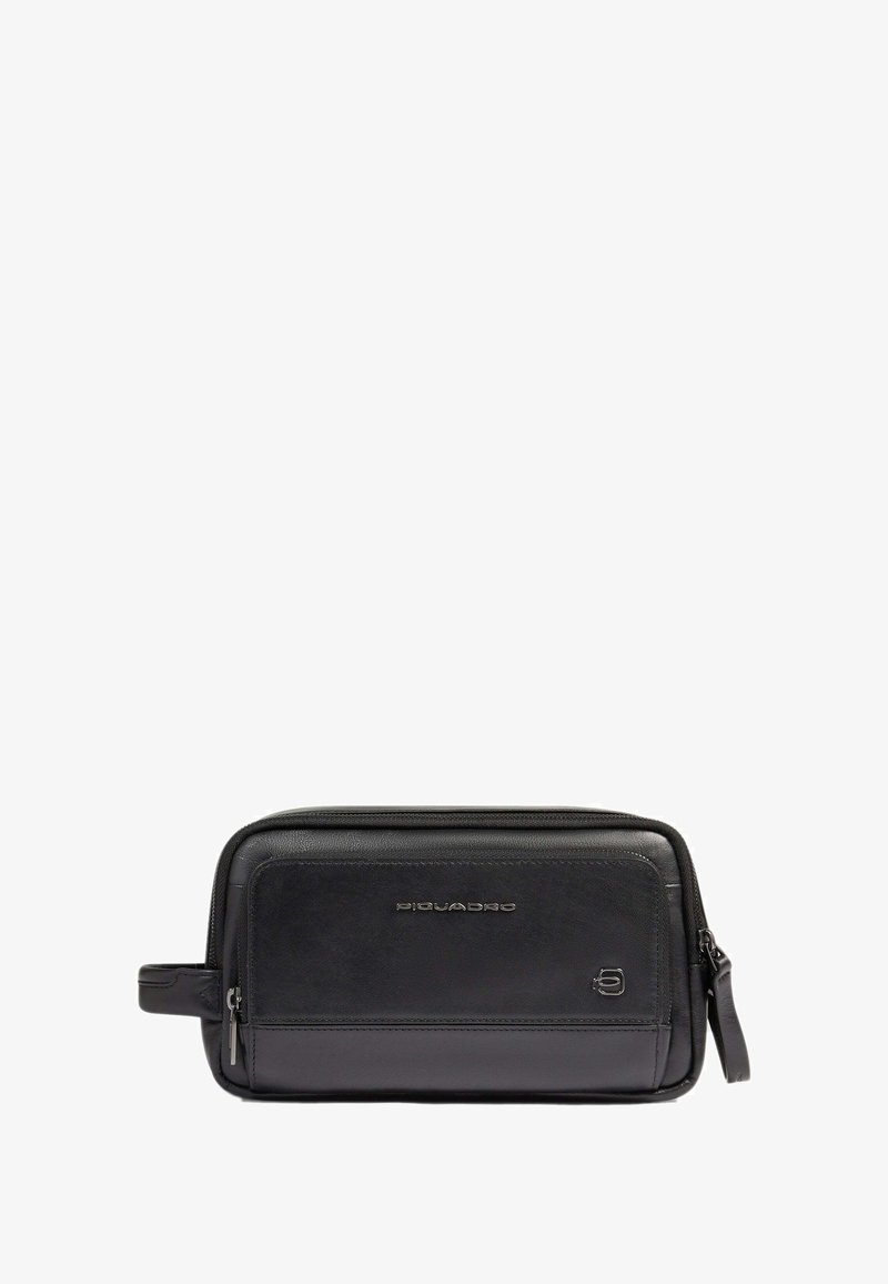 Pochette da viaggio in pelle nera con forma rettangolare, texture liscia, chiusura con zip e manico laterale. Presenta un branding sottile sulla parte anteriore.