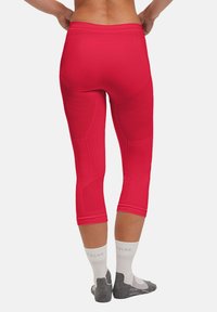 Rode capri leggins van rekbaar materiaal, met gestructureerde panelen en een slim fit ontwerp. Sokjes zichtbaar in een grijs-wit kleurenschema.