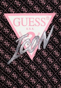 Czarna tkanina z powtarzającym się różowym wzorem logo. Duża różowa trójkątna łatka z napisem "GUESS U.S.A." oraz "ICON" w metalicznie srebrnym kolorze.