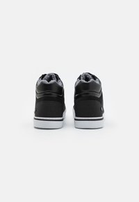 Zapatillas altas negras con parte superior de cuero suave y tela texturizada, suela de goma blanca y un suave forro gris.