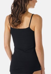 Camisola nera con sottili spalline regolabili, realizzata in un tessuto morbido ed elastico. Design aderente con una texture liscia e senza cuciture.