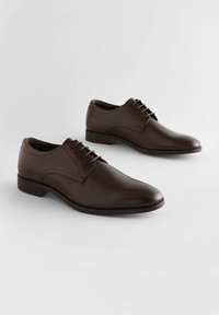 Zapatos de vestir de cuero marrón con un diseño elegante, puntera redondeada y cordones ligeros. Textura suave y detalles de costura minimalistas.