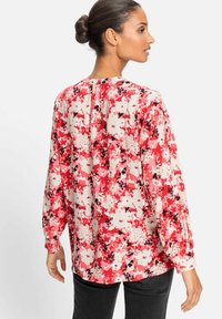 Blumenbluse in Pink, Rot und Weiß mit schwarzen Akzenten. Sie hat lange Ärmel, eine lässige Passform und eine geknöpfte Rückenansicht.