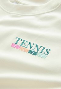 Biała bluza z haftem "TENNIS CLUB" w teal, różowych, pomarańczowych i zielonych blokach. Miękka tkanina z prążkowanym dekoltem.