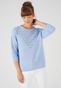 Maglione azzurro chiaro lavorato a maglia con una scollatura in pizzo decorato e maniche a tre quarti. La trama del tessuto è liscia e il fit è rilassato.