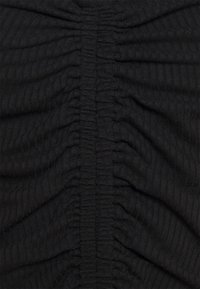 Tissu côtelé noir avec un détail froncé. La texture est douce avec des sections rassemblées créant un léger effet ondulé sur la surface.