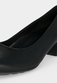 Escarpin noir pour femme à petit talon avec finition lisse et semelle intérieure rembourrée présentant de petites perforations pour le confort.