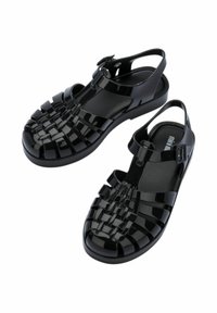 Czarne syntetyczne sandały z plecionym wierzchem, regulowanym paskiem i otwartym fasonem z tyłu. Posiadają płaską podeszwę i gładkie, błyszczące wykończenie.