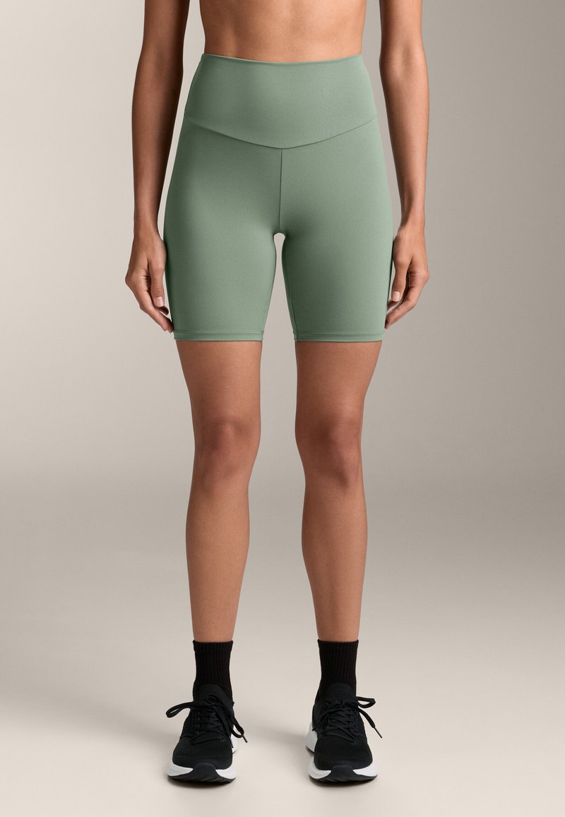 Vysoké zelené cyklistické šortky vyrobené z elastického materiálu, s hladkou textúrou a čistým dizajnom bez viditeľných vzorov.