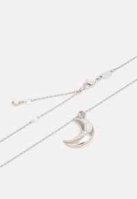 Collier en argent avec un pendentif en forme de croissant de lune au fini brillant, orné de petits cristaux transparents le long du bord inférieur.