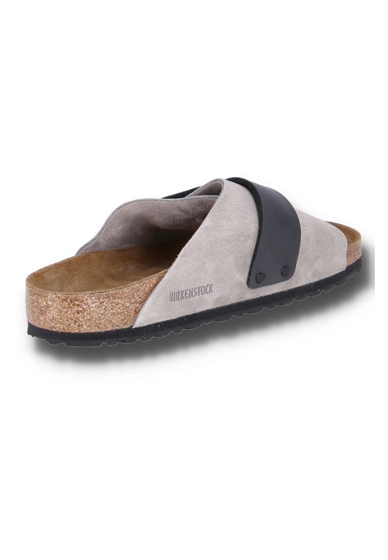 Grau Wildledersandale mit einem schwarzen Riemen, Kork-Zwischensohle und strukturiertem Gummi-Außensohle. Logo seitlich gestempelt. Abgerundetes Zehendesign.