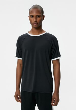 Camiseta negra de manga corta con ribete blanco en el escote y las mangas, hecha de tela suave, con un corte relajado y mangas raglán.