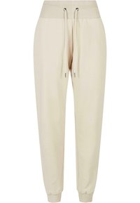 Beige Jogginghosen aus weichem Stoff. Verfügbar mit einem gerippten, elastischen Bund und Kordelzügen sowie schmal zulaufenden Bündchen. Sanfte Textur, keine Muster.