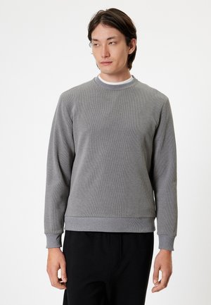 Grå ribbet sweatshirt med lange ærmer, rund halsudskæring og en struktureret overflade. Har en tætsiddende talje og manchetter. Minimalistisk design.