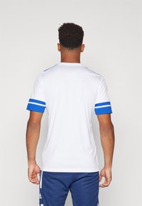 White sports shirt with blue accents on sleeves; features horizontal stripes on cuffs. The fit is athletic, with a round neckline and soft texture.