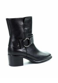 Botte en cuir noire mi-mollet avec talon épais et large sangle ornée d'une grande boucle circulaire argentée sur le côté.