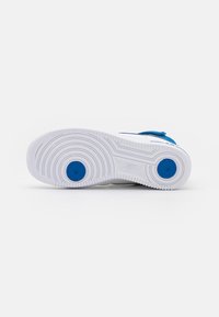 Witte sneakerzool met cirkelvormige blauwe accenten en gestructureerde grippatronen. Gladde rubberen materiaal met uitgesproken loopvlakontwerp voor grip.