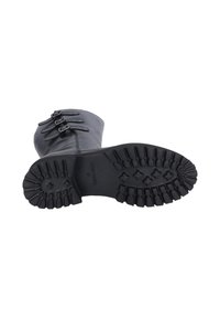 Bota de cuero negra con tres hebillas decorativas, puntera redondeada y suela de goma texturizada con tacos profundos para tracción.
