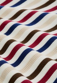 Getextureerde stof met horizontale geribbelde strepen in wit, rood, marineblauw, beige en bruin, weergegeven in zachte plooien.