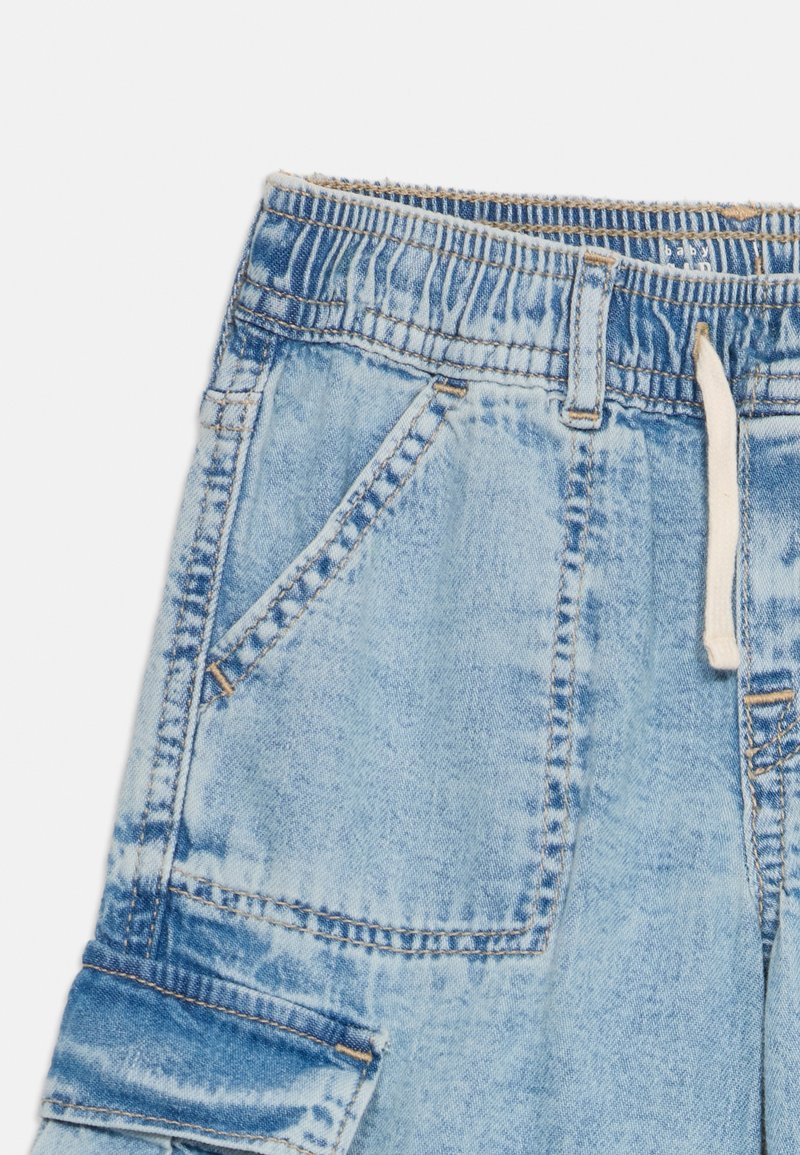 Shorts cargo en denim bleu clair avec une taille élastique, des poches latérales, des coutures visibles et un cordon de serrage pour un ajustement réglable.