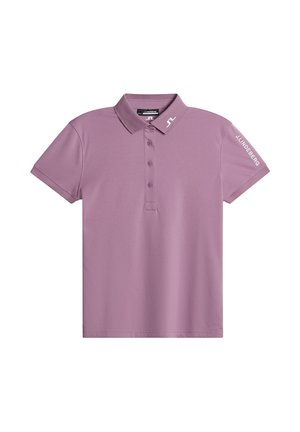 Kortärmad polo skjorta i ljus lila, tillverkad av ett slätt tyg. Har en krage, treknappsknäppning och logotypdetaljer på ärmen.