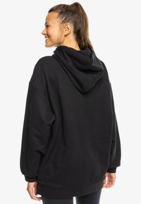 Schwarzer Kapuzenpullover mit lockerer Passform, langen Ärmeln mit gerippten Bündchen und einer weichen Textur. Keine sichtbaren Muster oder Hardware-Details.