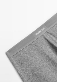 Grå boxershorts gjorda av ett mjukt material, med ett brett elastiskt midjeband med "Massimo Dutti"-logotyp och en slät textur.