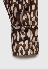 Polsino di camicia con stampa leopardata marrone e beige, caratterizzato da un tessuto liscio, tre bottoni neri e un design pulito e sartoriale.