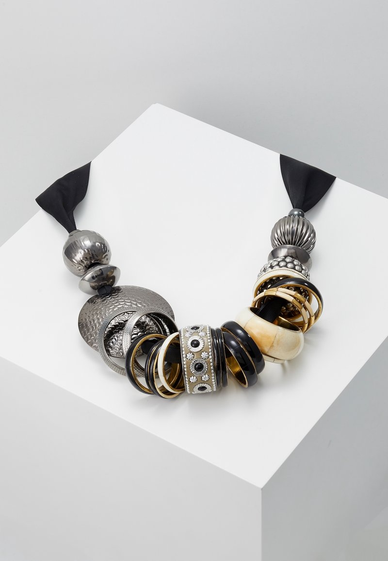 Collier épais avec anneaux et perles métalliques mélangés en argent, or, noir et crème sur un cordon en tissu noir.