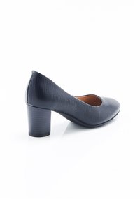 Zapato de tacón alto en material texturizado de un azul marino oscuro, con punta redonda y tacón cuadrado. Forro interior suave visible en la abertura.