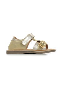 Sandalias metálicas doradas con punta y laterales abiertos, que cuentan con una correa de velcro y un detalle de hebilla rectangular. Suela plana y material de cuero suave.