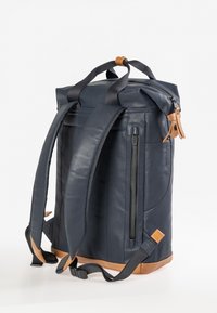 Zaino blu navy con dettagli in pelle, design a roll-top, spallacci regolabili e tasca laterale con cerniera. Finitura texturizzata e base robusta.