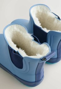 Stivali in gomma blu con morbida fodera in pile bianco, pannelli laterali elastici navy testurizzati e linguette per indossarli facilmente.