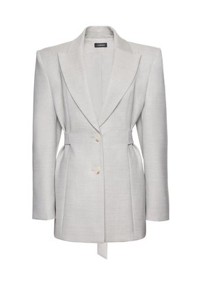 Světle šedé sako na míru s vycpanými rameny, dvěma knoflíky vpředu, klopami s výstřihem a detailem staženého pasu od La Mania.