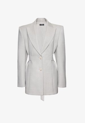 Světle šedé sako na míru s vycpanými rameny, dvěma knoflíky vpředu, klopami s výstřihem a detailem staženého pasu od La Mania.