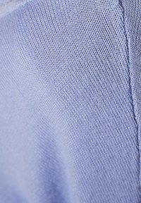 Tissu tricoté bleu clair présentant une surface texturée avec des côtes diagonales et une couture nette, mettant en valeur la douceur et la finition du matériau.